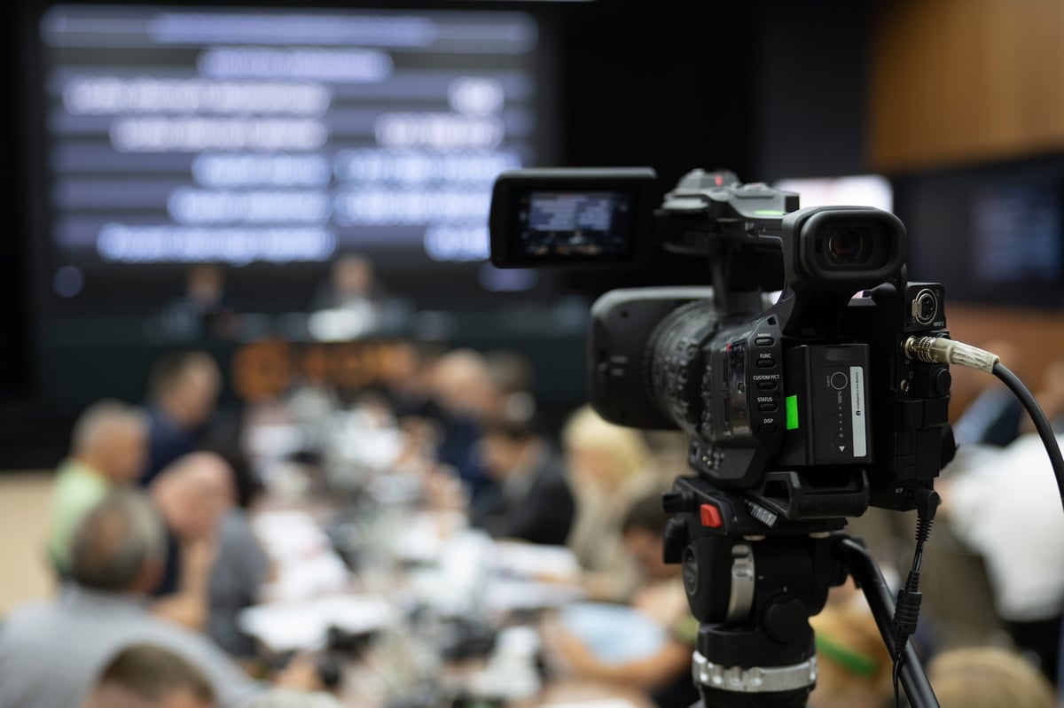 Cámara de televisión durante una conferencia de prensa con el vocero al fondo